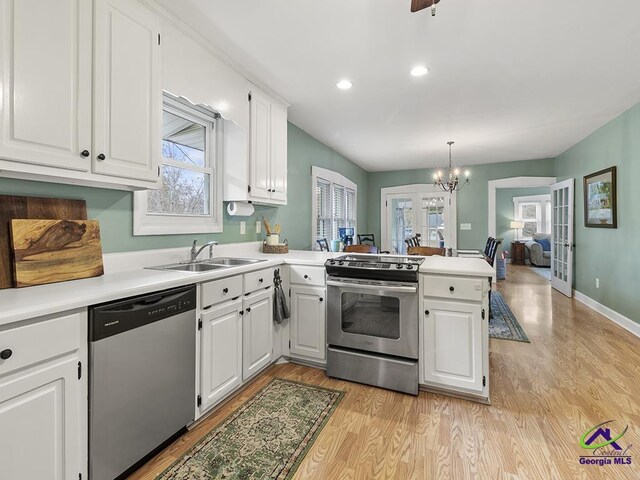 kitchen with kitchen peninsula, appliances with stainless steel finishes, decorative light fixtures, white cabinets, and light wood-type flooring