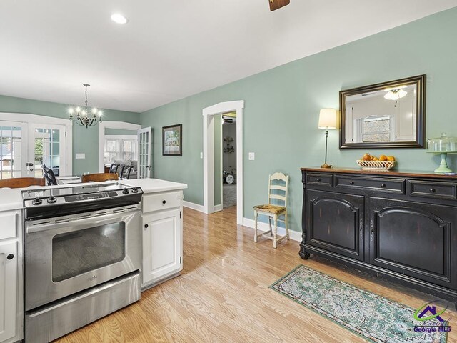 kitchen featuring french doors, light hardwood / wood-style floors, stainless steel range oven, white cabinetry, and a chandelier