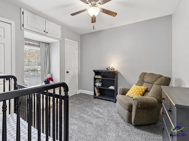 carpeted bedroom with ceiling fan and a nursery area