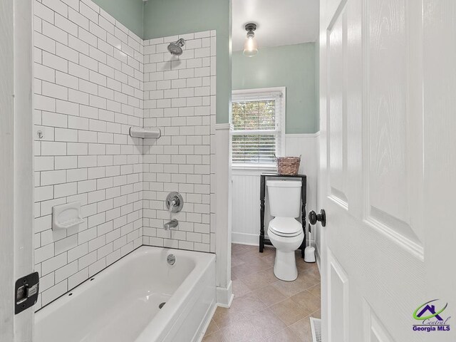 bathroom featuring tile patterned flooring, tiled shower / bath combo, and toilet