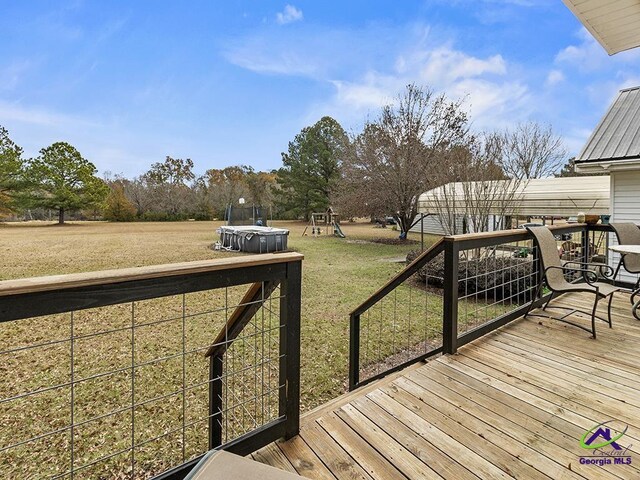 wooden deck featuring a playground and a lawn