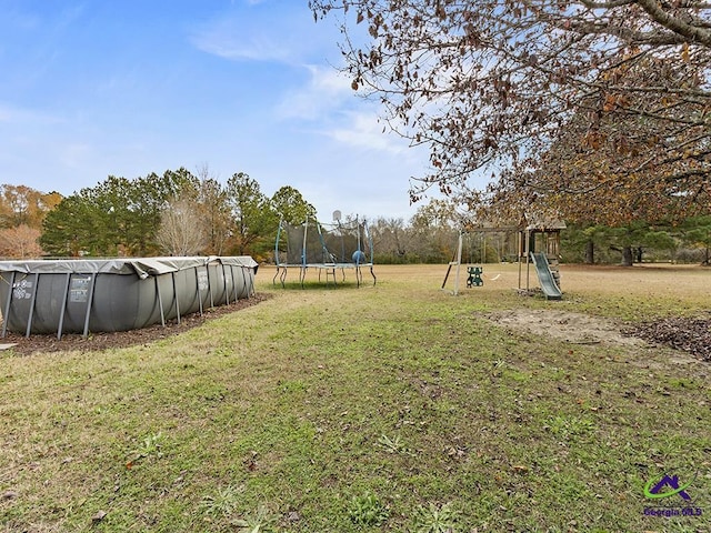 view of yard with a playground, a covered pool, and a trampoline