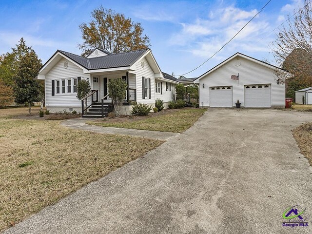 ranch-style home with a front yard, a garage, an outdoor structure, and covered porch