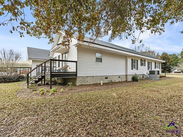 view of home's exterior with a lawn and central AC