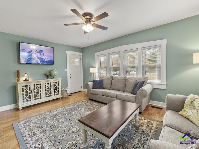 living room featuring plenty of natural light, ceiling fan, and light wood-type flooring