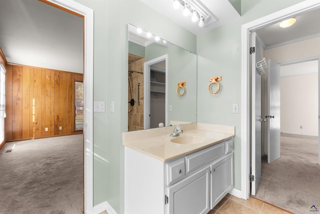 bathroom with tile patterned floors, a shower, crown molding, wooden walls, and vanity