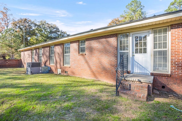 rear view of property with a yard and central air condition unit