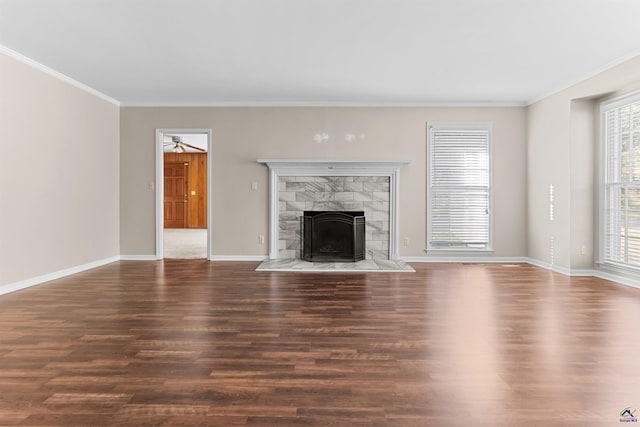 unfurnished living room featuring dark hardwood / wood-style flooring, a stone fireplace, ceiling fan, and crown molding