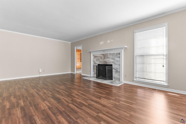 unfurnished living room featuring crown molding, dark wood-type flooring, and a tiled fireplace