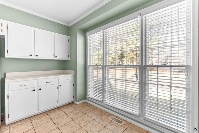 kitchen featuring white cabinets, crown molding, and light tile patterned floors