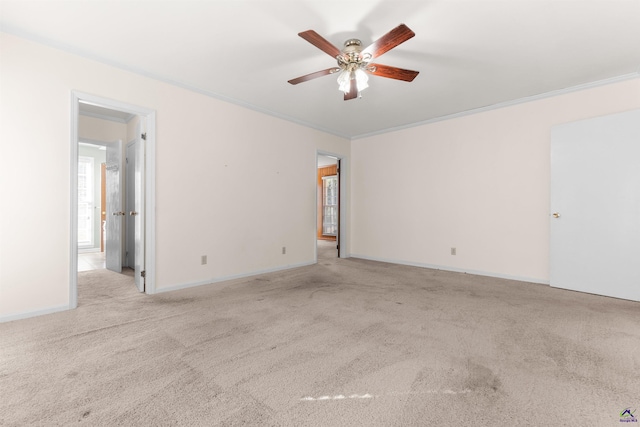 empty room featuring ceiling fan, crown molding, and light carpet