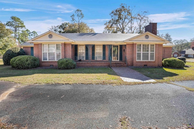 ranch-style home featuring covered porch and a front lawn