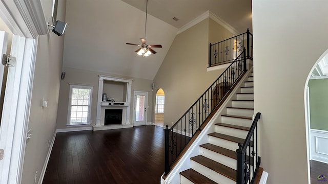 stairs featuring ceiling fan, crown molding, high vaulted ceiling, and wood-type flooring