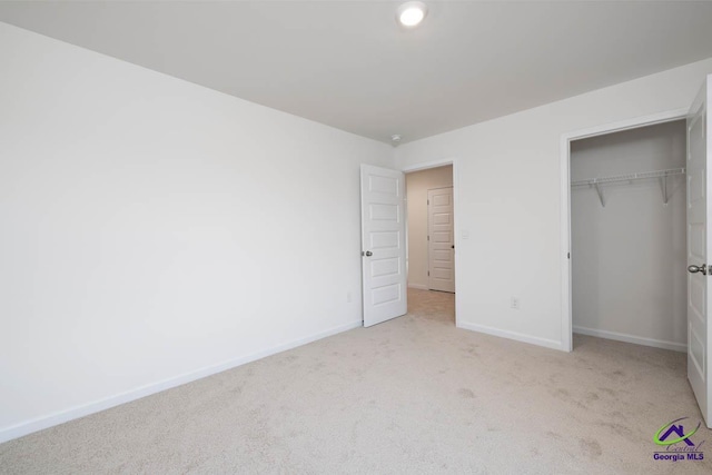 unfurnished bedroom featuring light carpet and a closet