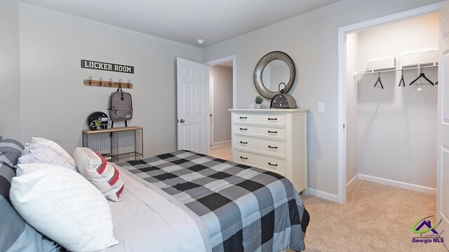 bedroom with a spacious closet, light carpet, and a closet