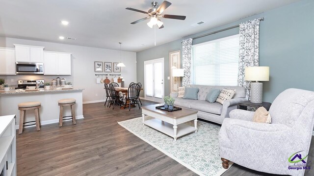 living room with dark hardwood / wood-style floors and ceiling fan