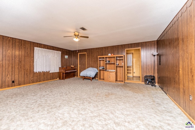 unfurnished room featuring carpet floors, ceiling fan, and wooden walls