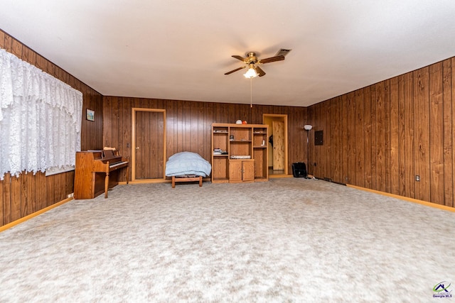 unfurnished room with carpet, wooden walls, and ceiling fan