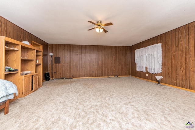 unfurnished living room with carpet flooring, ceiling fan, and wooden walls