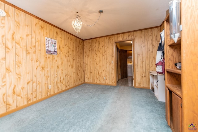 carpeted spare room featuring crown molding, wooden walls, and a chandelier