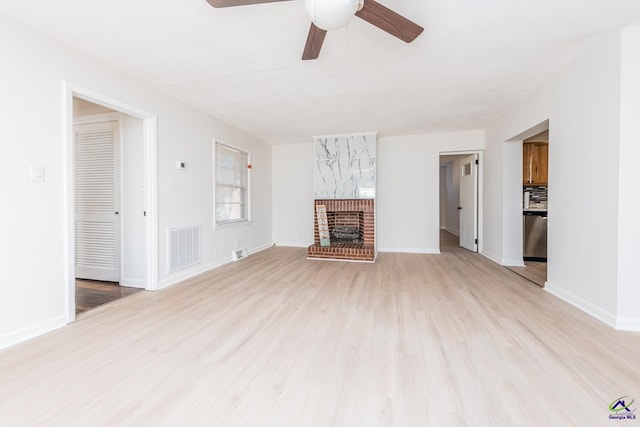 unfurnished living room featuring ceiling fan, a fireplace, and light hardwood / wood-style flooring