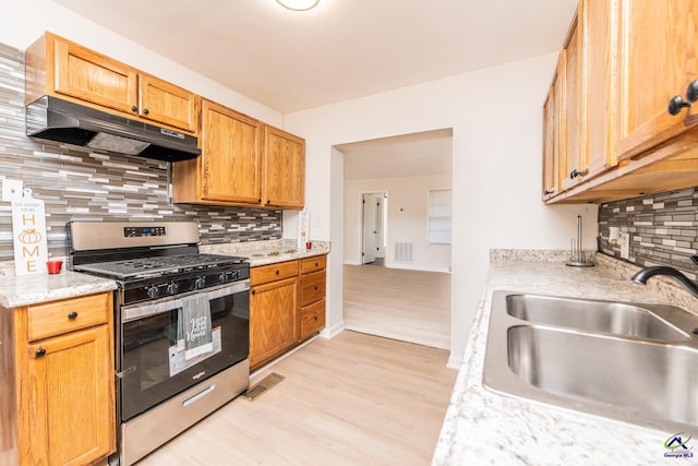 kitchen featuring gas stove, tasteful backsplash, light hardwood / wood-style floors, and sink