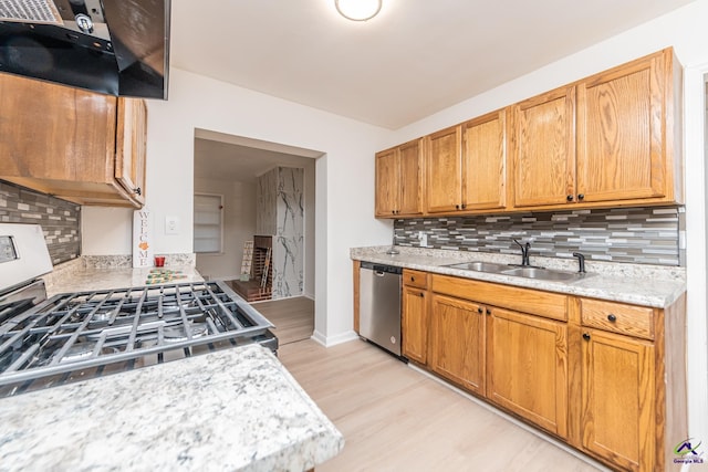 kitchen featuring appliances with stainless steel finishes, light wood-type flooring, tasteful backsplash, sink, and exhaust hood