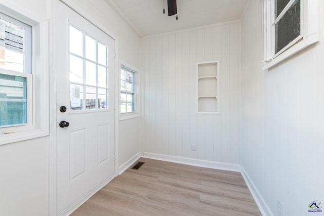 entryway featuring light hardwood / wood-style floors, ornamental molding, and wooden walls