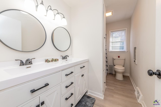 bathroom with wood-type flooring, vanity, and toilet