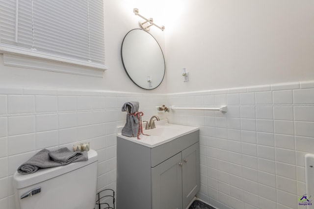 bathroom featuring vanity, tile walls, and toilet