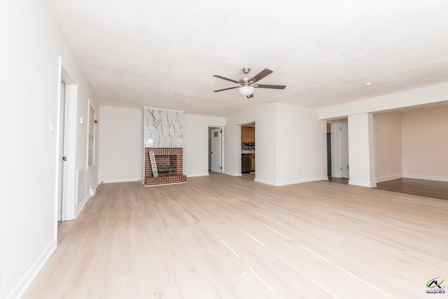 unfurnished living room with a fireplace, light hardwood / wood-style flooring, and ceiling fan