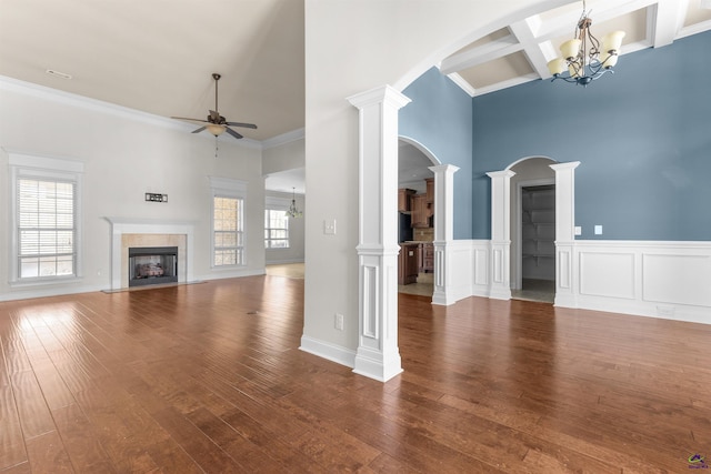 unfurnished living room featuring ornate columns, a wealth of natural light, and hardwood / wood-style flooring