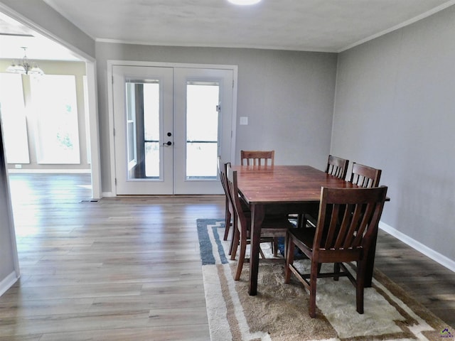 dining space with crown molding, french doors, a chandelier, and hardwood / wood-style flooring