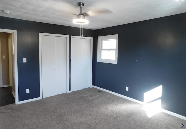 unfurnished bedroom with carpet, two closets, and ceiling fan