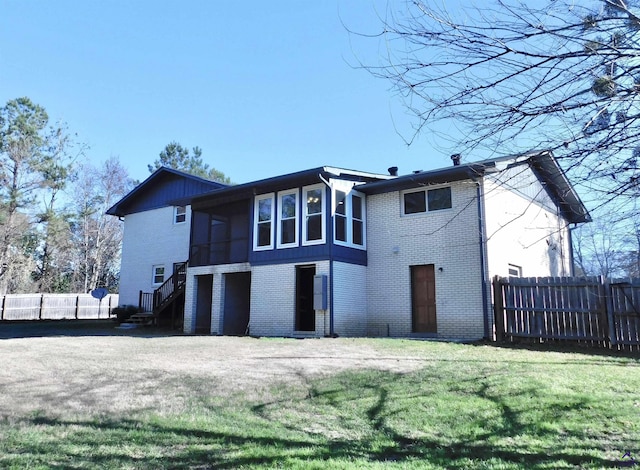 rear view of house with a lawn and a sunroom