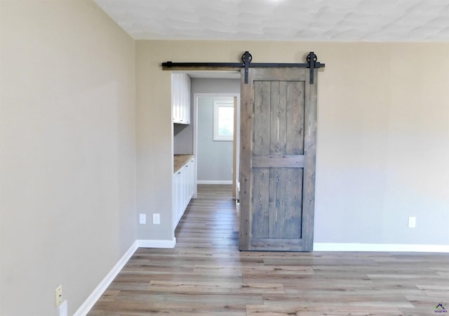 empty room featuring a barn door and light wood-type flooring