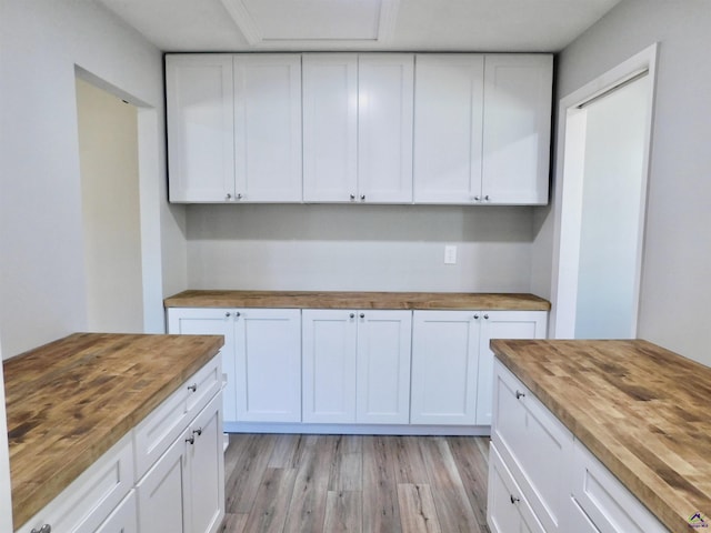 kitchen with butcher block counters, white cabinets, and light hardwood / wood-style floors