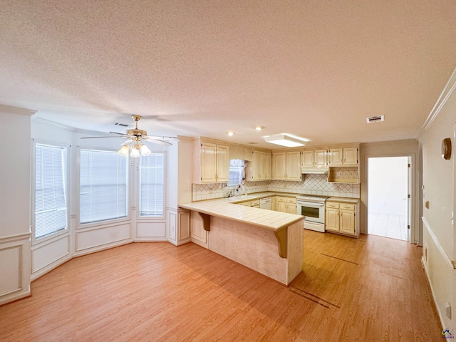 kitchen with ceiling fan, tile countertops, white appliances, decorative backsplash, and ornamental molding