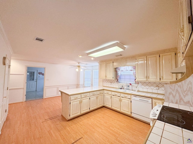 kitchen featuring kitchen peninsula, light wood-type flooring, white appliances, sink, and tile counters