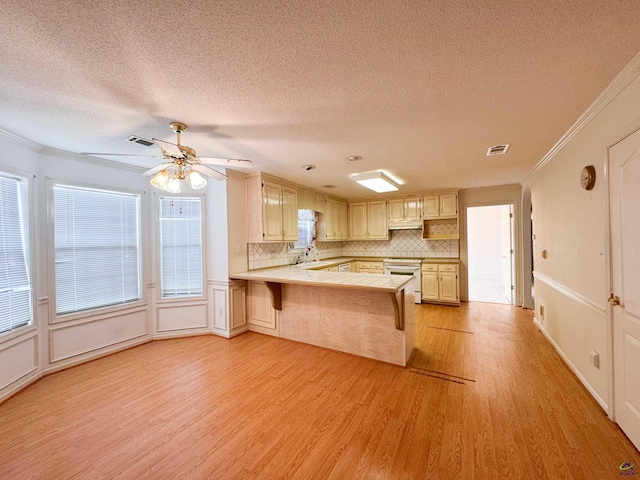 kitchen featuring a breakfast bar, light wood-type flooring, kitchen peninsula, and tasteful backsplash