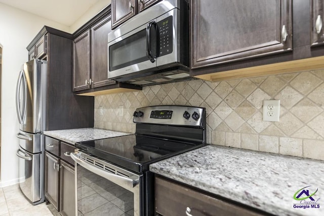 kitchen with light tile patterned floors, light stone countertops, appliances with stainless steel finishes, tasteful backsplash, and dark brown cabinets