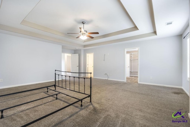 empty room with ceiling fan, carpet floors, and a tray ceiling