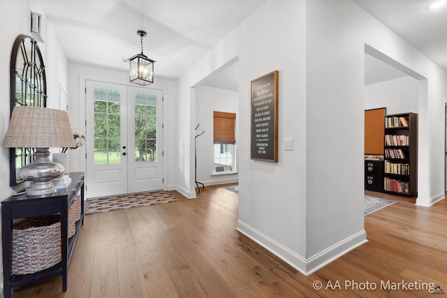 foyer featuring a chandelier, light hardwood / wood-style flooring, a healthy amount of sunlight, and french doors