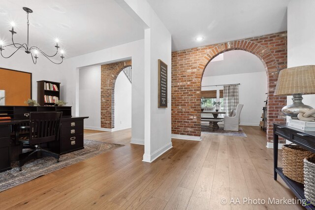 office area featuring light hardwood / wood-style flooring, a chandelier, and brick wall