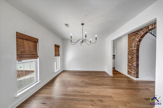 unfurnished dining area with a notable chandelier and hardwood / wood-style flooring