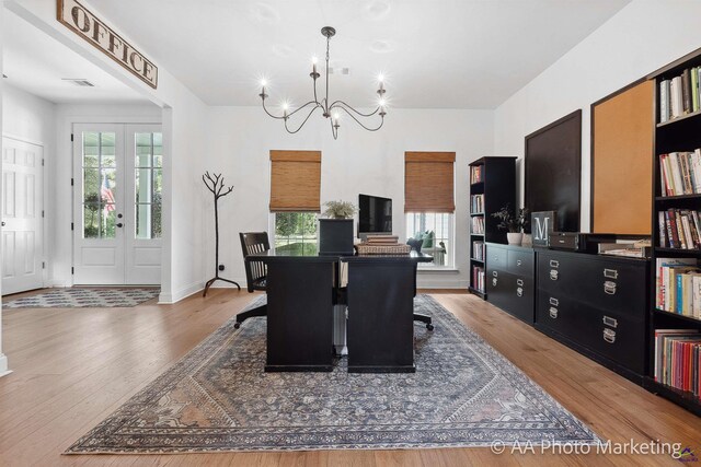 dining room featuring wood-type flooring, french doors, and an inviting chandelier