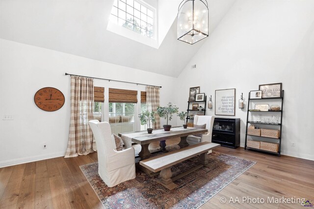 dining area featuring a notable chandelier, wood-type flooring, and a towering ceiling