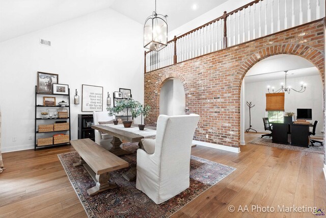 dining room with a notable chandelier, light hardwood / wood-style floors, and high vaulted ceiling