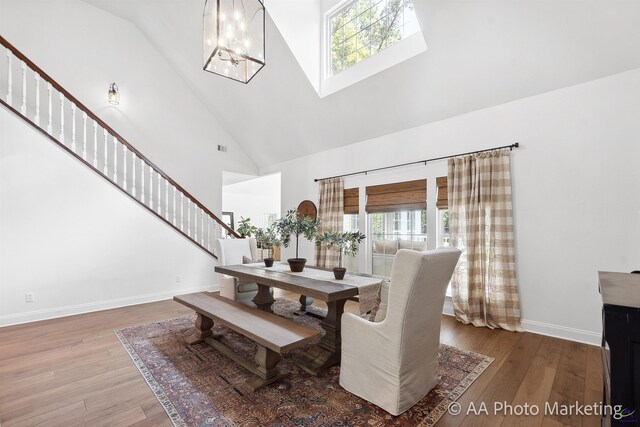 dining room featuring high vaulted ceiling, wood-type flooring, and a notable chandelier