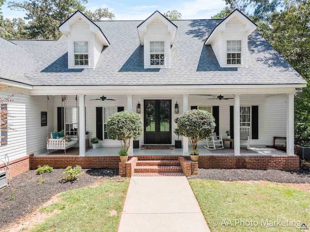 cape cod-style house with a front lawn, ceiling fan, covered porch, and french doors